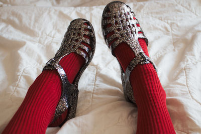 Low section of woman wearing red socks and sandals on bed