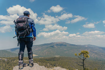 Rear view of man standing on mountain against sky