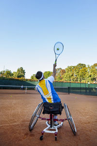 Disabled tennis player in wheelchair playing a match on an outdoor clay court