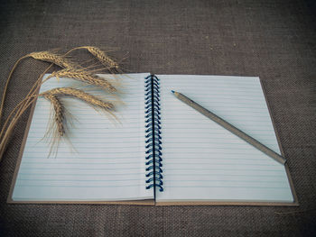 High angle view of pencil and open book on burlap