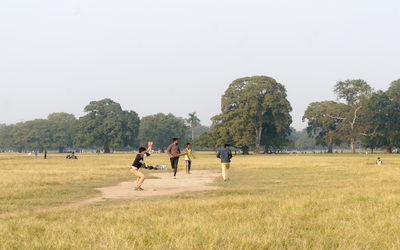 People playing on field against clear sky