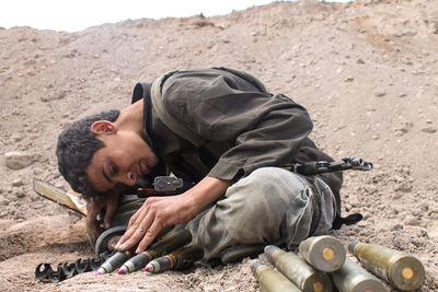 Boy sitting with gun on land