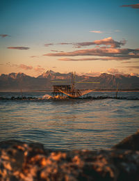 Fishing net on sea against sky during sunset