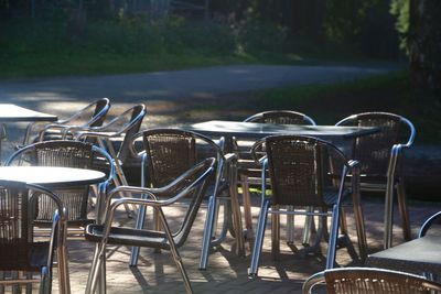 Empty tables and chairs arranged at sidewalk cafe