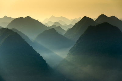 Scenic view of silhouette mountains during sunrise