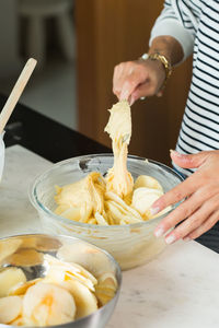 Woman putting dough in the baking dish while cooking apple pie in the modern kitchen