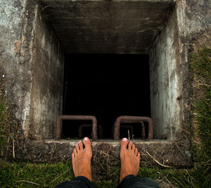 Low section on man standing by open sewer