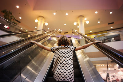Low angle view of girl standing on escalator