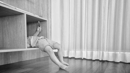 Low section of boy lying in shelf