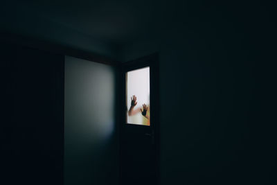Woman standing by window in darkroom