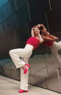 Full length of young woman  stands near a mirrored wall