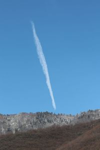 Low angle view of vapor trail against clear blue sky