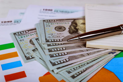 Close-up of pen and book on paper currency at table