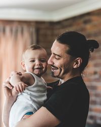 Side view of smiling father carrying son at home