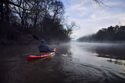 Rear view of man kayaking on chattahoochee river against sky