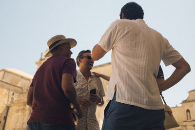 Rear view of men standing against sky