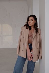 Portrait of young woman standing against wall