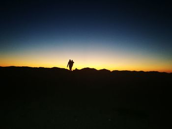 Silhouette man standing on land against sky during sunset