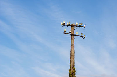 Low angle view of cross on street light against sky