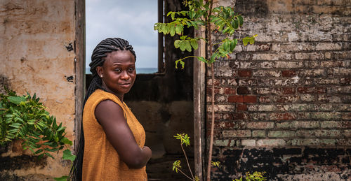 A ghanaian woman stands at the doorway of a demolished building