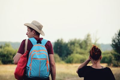 Rear view of couple standing on field against clear sky