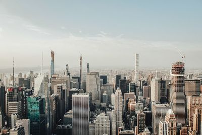 Aerial view of buildings in city against cloudy sky