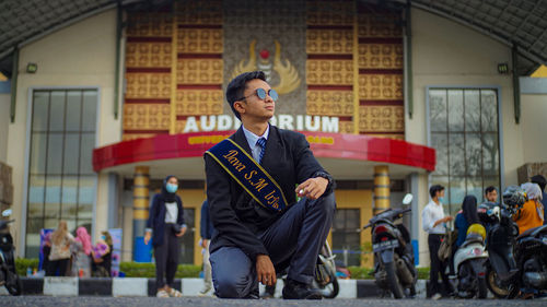 Full length of young man standing against building