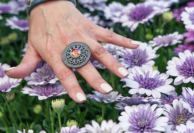 Cropped hand showing ring over purple flowers in field