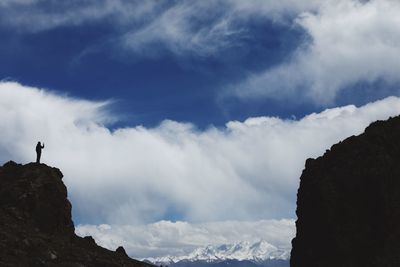 Low angle view of person on rocks against sky