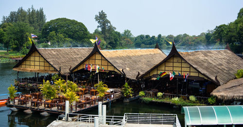 Houses and trees by lake against sky