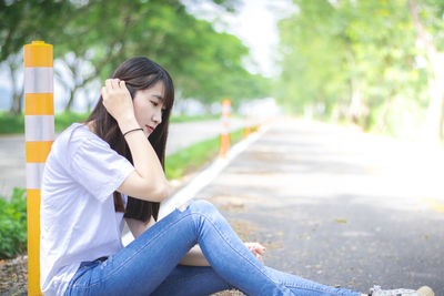 Side view of a young woman sitting on road