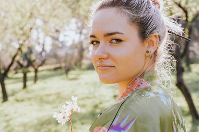 Portrait of beautiful woman standing by flowering plants