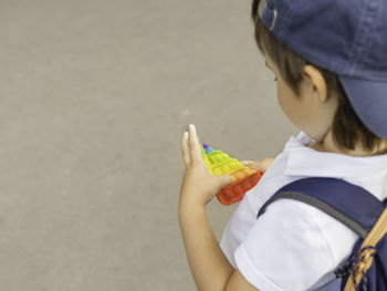 Boy plays square rubber fidget toy pop it. rainbow-colored anti stress tactile toy for all ages.