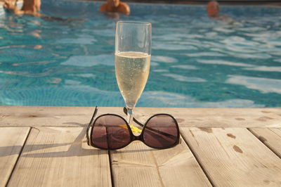 Glass of water on table at swimming pool