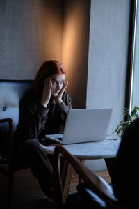 Worried woman sitting with laptop in cafe