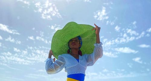 Full length portrait of girl standing against sky in a big green hat