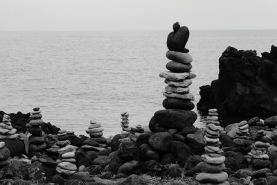Stack of stones by sea against sky