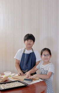 Portrait of happy siblings and woman on table