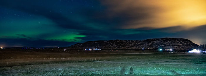 Scenic view of illuminated landscape against dramatic sky at night