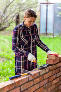 Young woman bricklayer lay out cement mortar for brickwork with a trowel on a brick wall