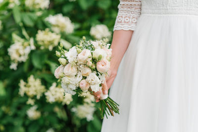The bride holds in her hands a beautiful wedding bouquet of white and peach flowers
