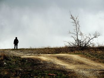 Rear view of man standing on field against sky