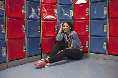 A young woman by some red and blue lockers.