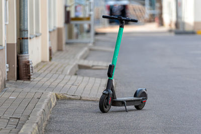 Green e-scooter for rent parked on street, electric scooter for public sharing, modern eco-transport