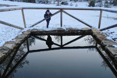 Boy standing at snow covered lakeshore