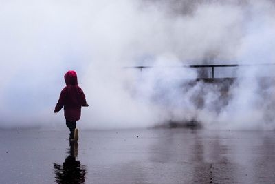 Rear view of woman standing in water against sky