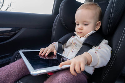 Boy using digital tablet while sitting in car