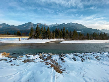 Scenic view of frozen lake by snowcapped mountains against sky