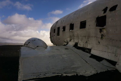 Abandoned airplane on beach against sky