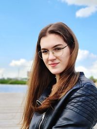 Portrait of beautiful young woman at pier against sky